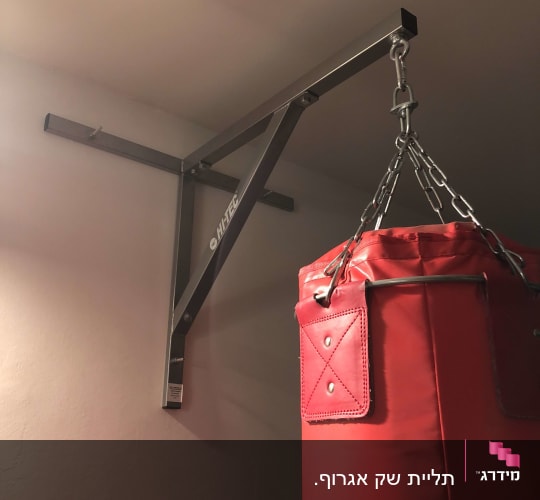 שק אגרוף תלוי על מתקן מתכת לקיר